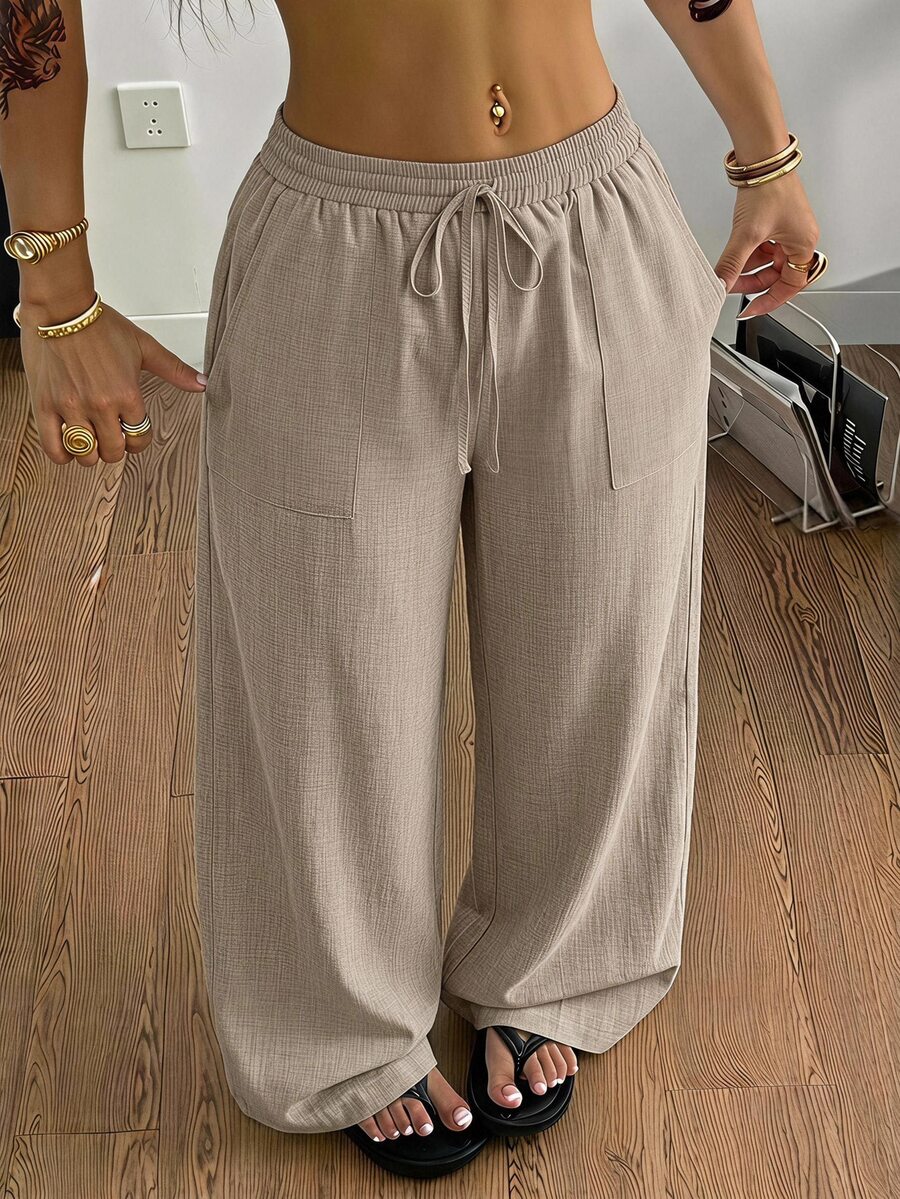 Women's loose straight leg cotton pants featuring a high waist with an adjustable drawstring knot and functional side pockets.