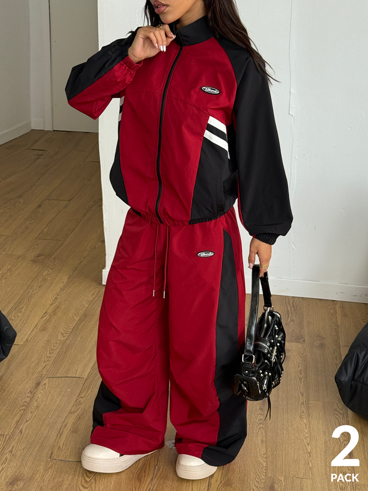 Women's plus size two-piece casual tracksuit set in black, featuring a loose-fit zip-up jacket with stand collar and matching cropped parachute pants.