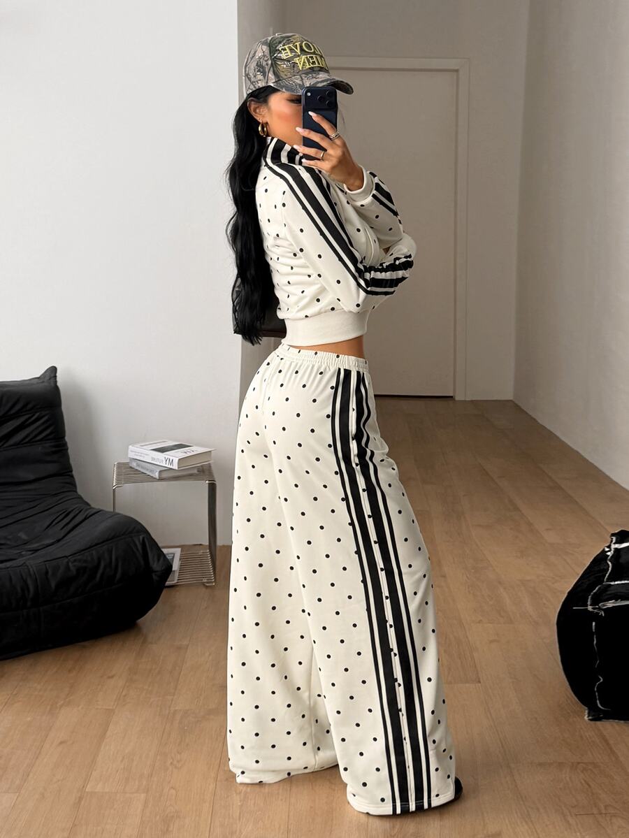 Women's two-piece black and white polka dot set featuring a short zip-up mock neck sweatshirt and matching wide-leg sweatpants.
