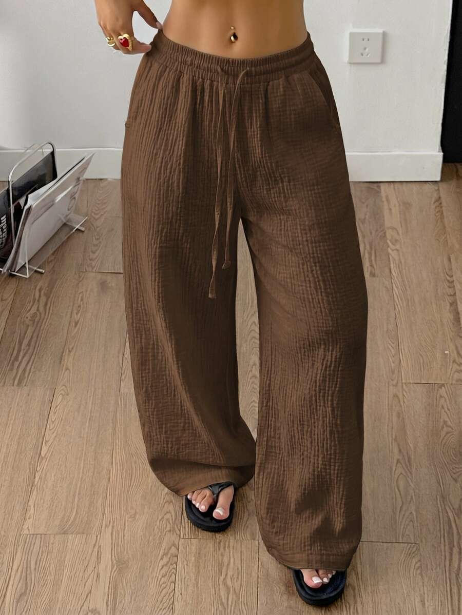 Women's black and white striped wide leg pants featuring an adjustable drawstring waist and side pockets.
