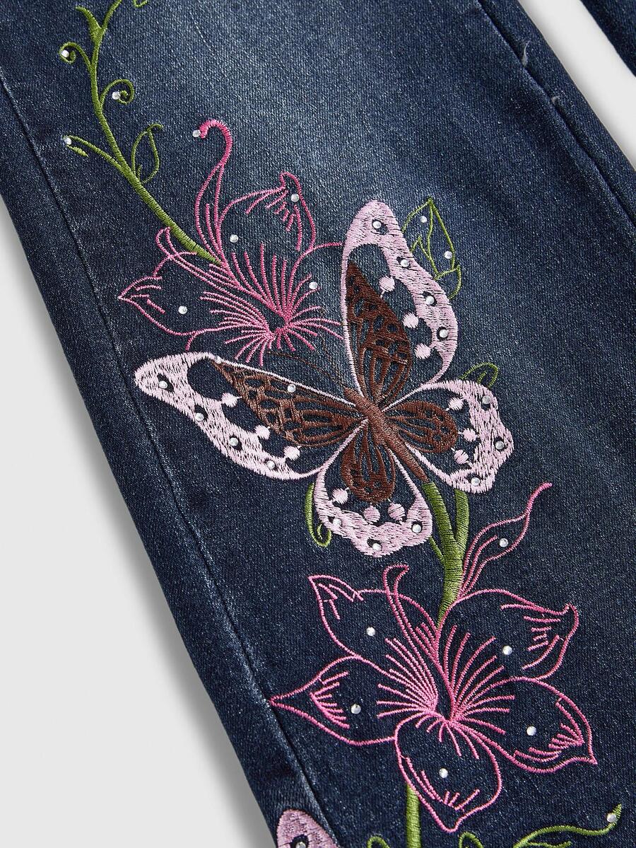 Women's blue ultra low waist flare jeans with butterfly vine embroidery and rhinestone detailing on stretch denim.