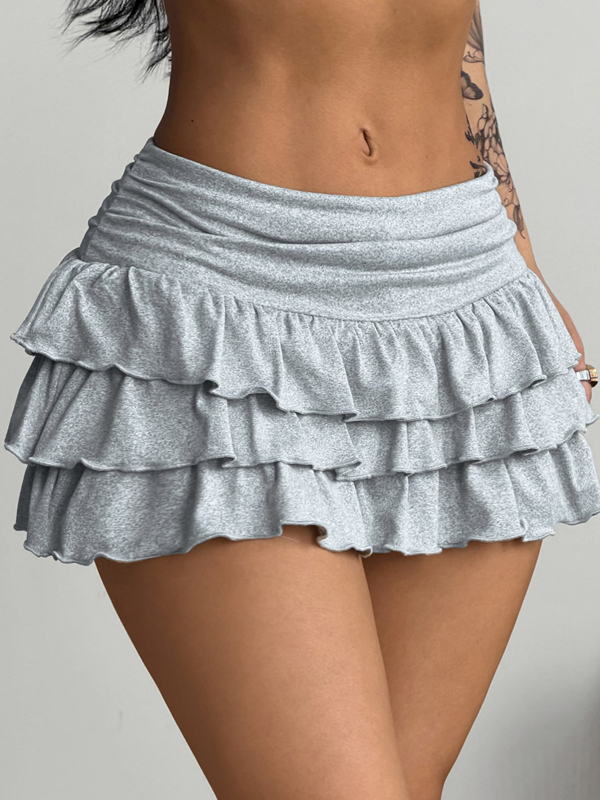 Women's white low waist tiered mini skirt featuring ruched detailing and a slight-stretch knitted fabric.