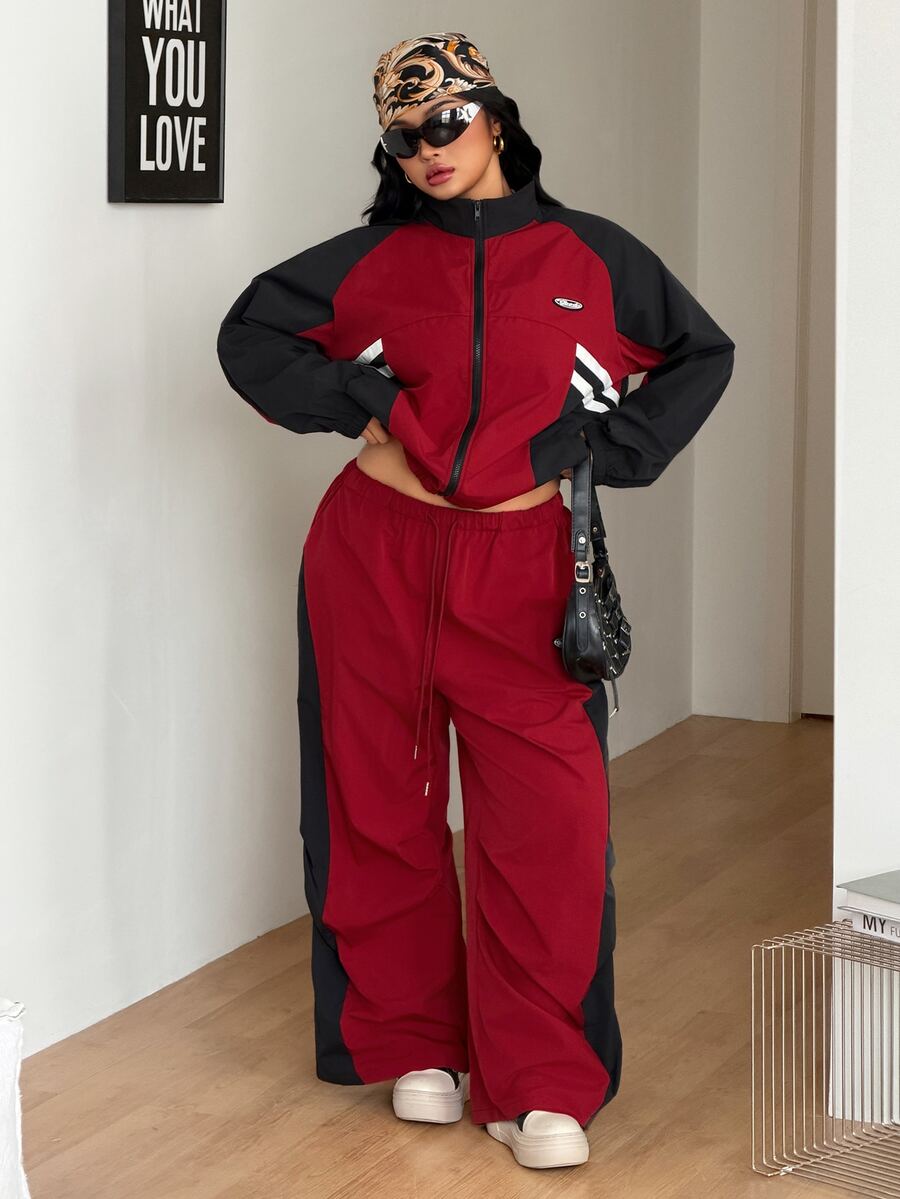 Women's plus size two-piece casual tracksuit set in black, featuring a loose-fit zip-up jacket with stand collar and matching cropped parachute pants.