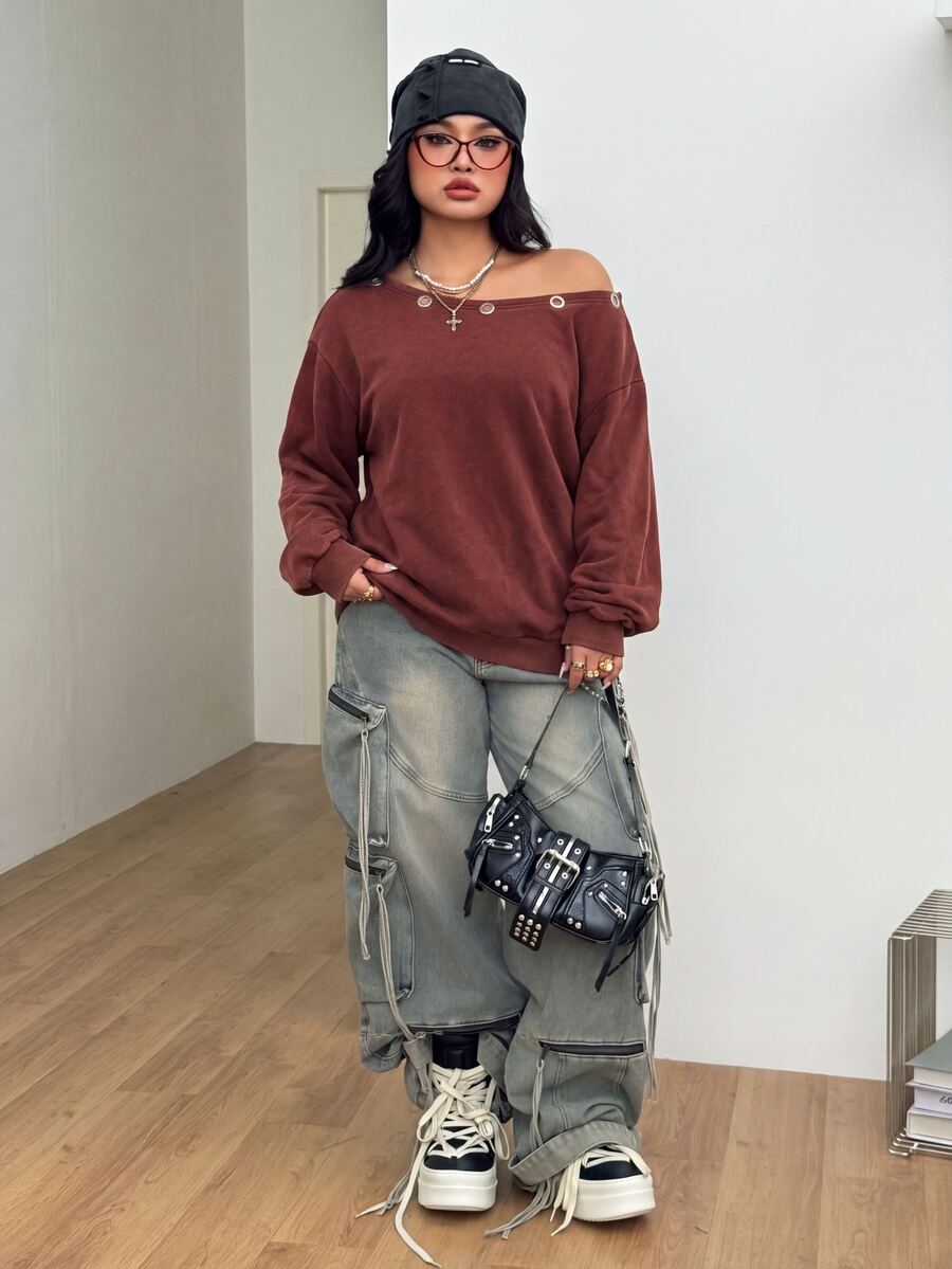 Women's oversized dark grey long sleeve sweatshirt featuring an asymmetrical boat neckline with grommet eyelet details and drop shoulders.