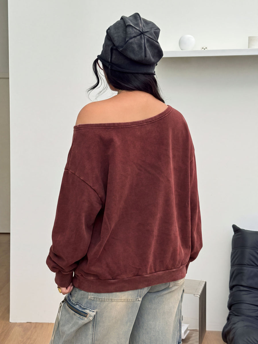 Women's oversized dark grey long sleeve sweatshirt featuring an asymmetrical boat neckline with grommet eyelet details and drop shoulders.
