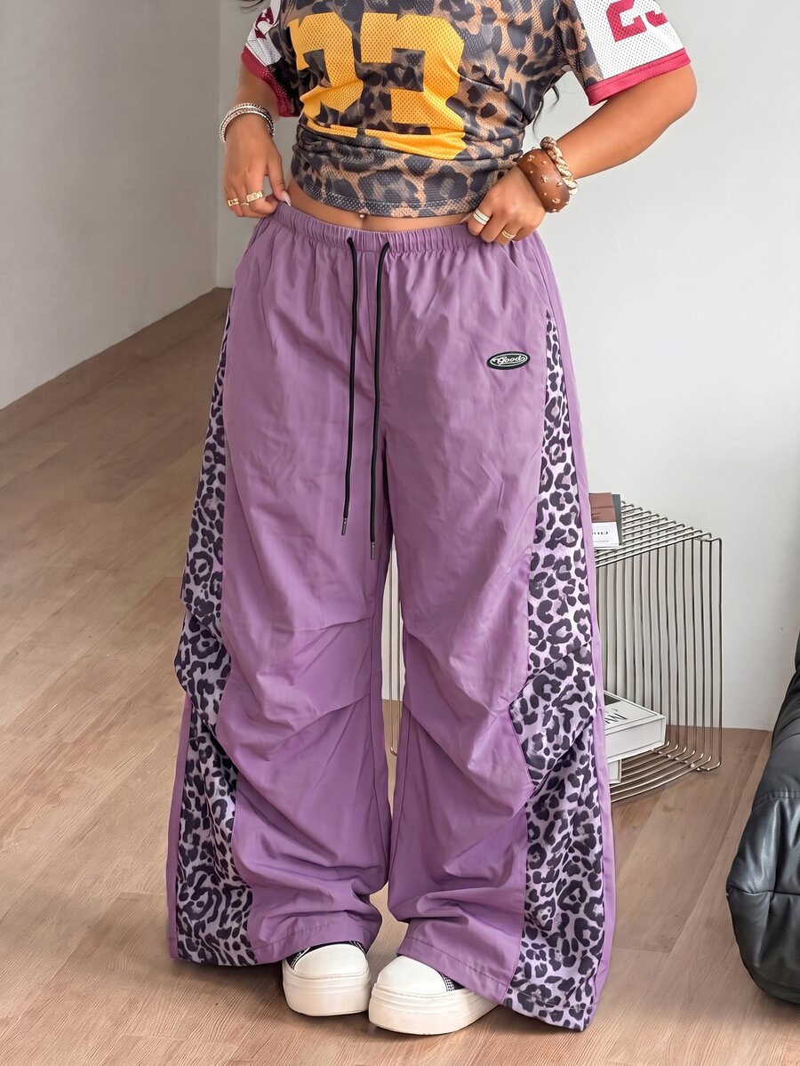 Women's high waist wide leg pants in black featuring leopard print patchwork details and an elastic drawstring waistband.