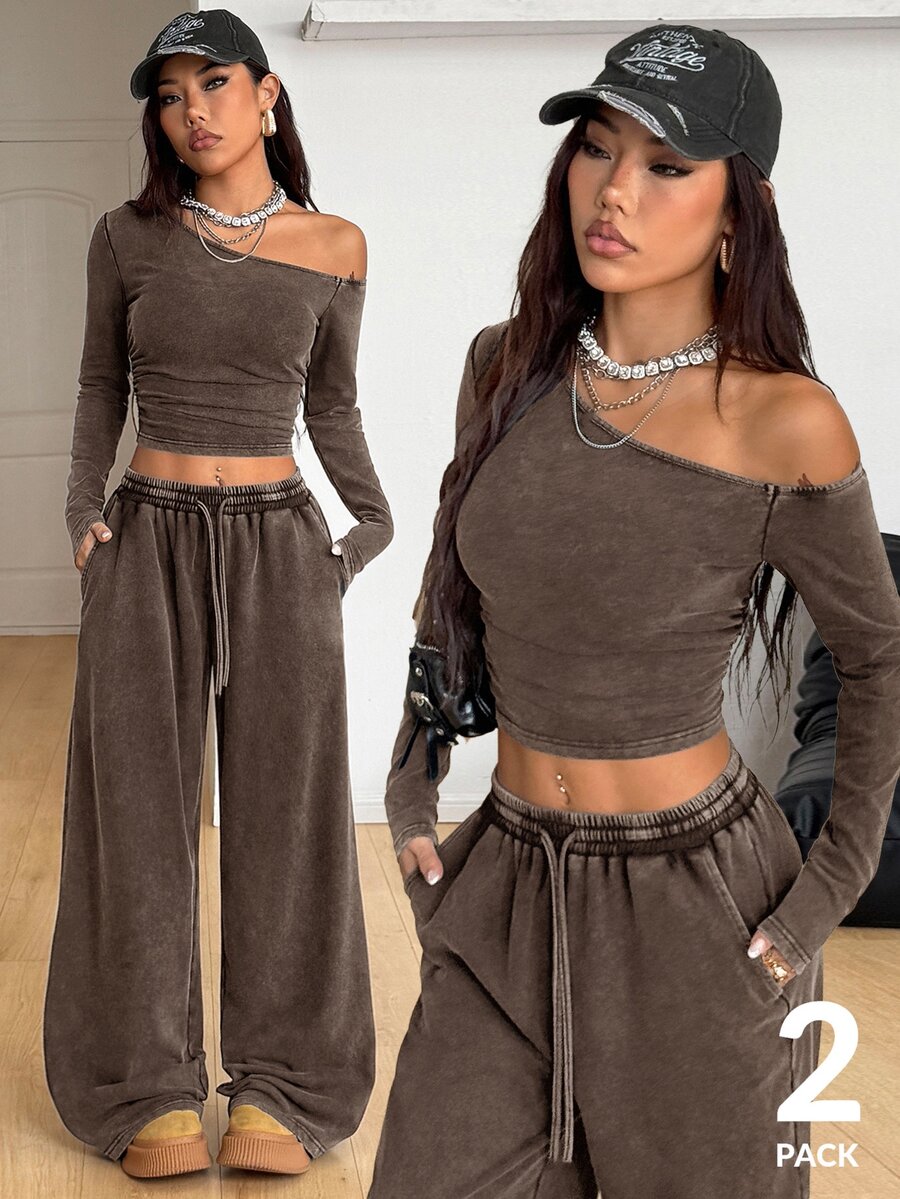 Women's two-piece knit lounge set featuring a black long sleeve asymmetrical crop top and matching high-waisted wide leg sweatpants.