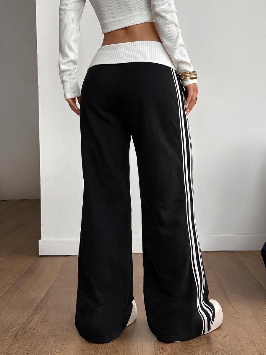 Women's wide leg flare sweatpants featuring a black and white colorblock contrast fold waistband and side stripe details.