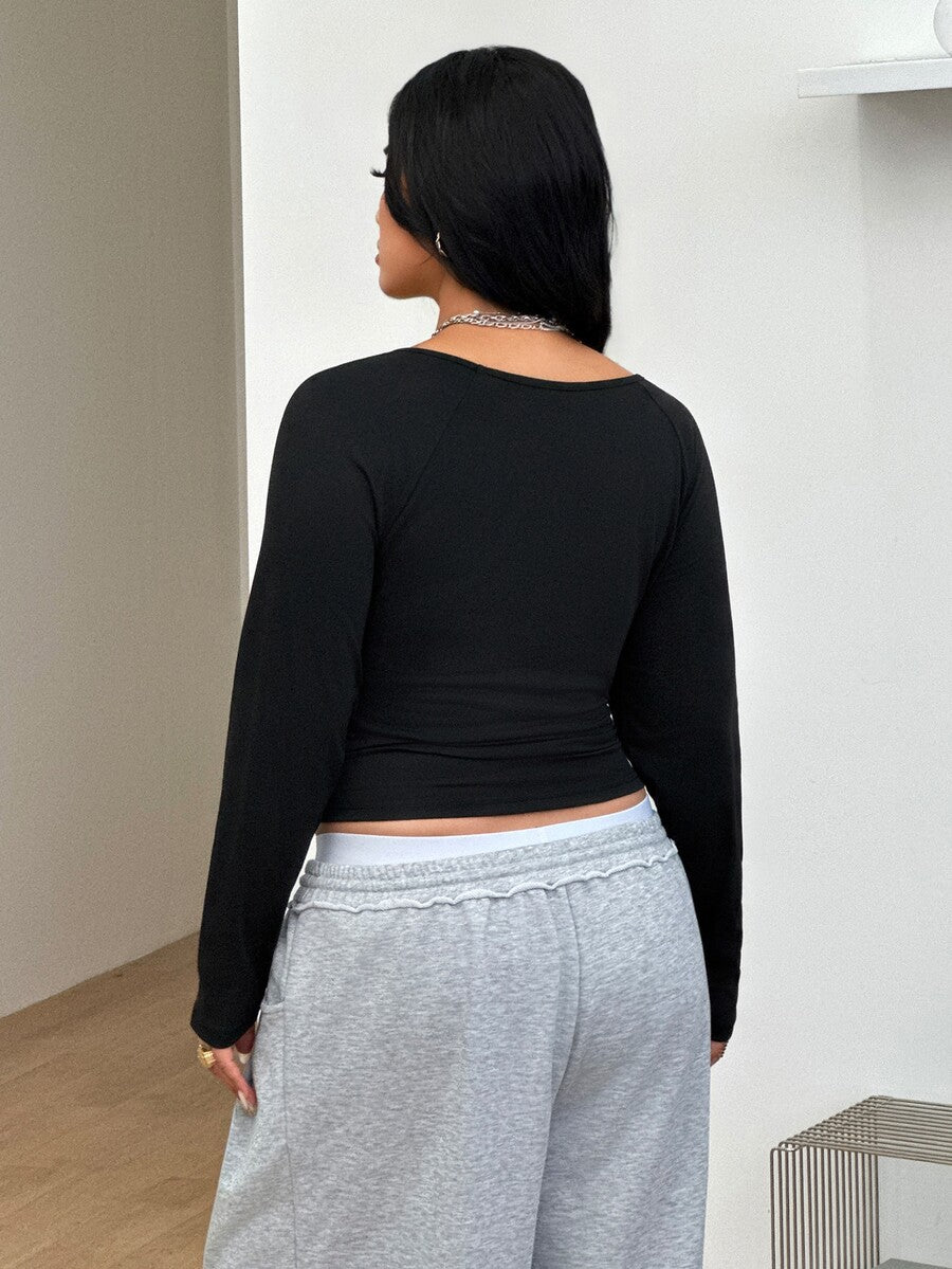 Women's plus size black and white colorblock long sleeve t-shirt with raglan sleeves and scoop neckline.