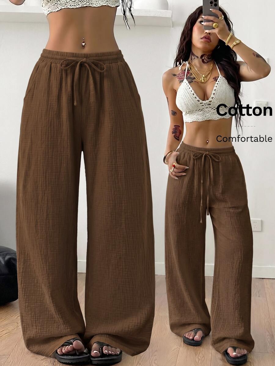 Women's black and white striped wide leg pants featuring an adjustable drawstring waist and side pockets.