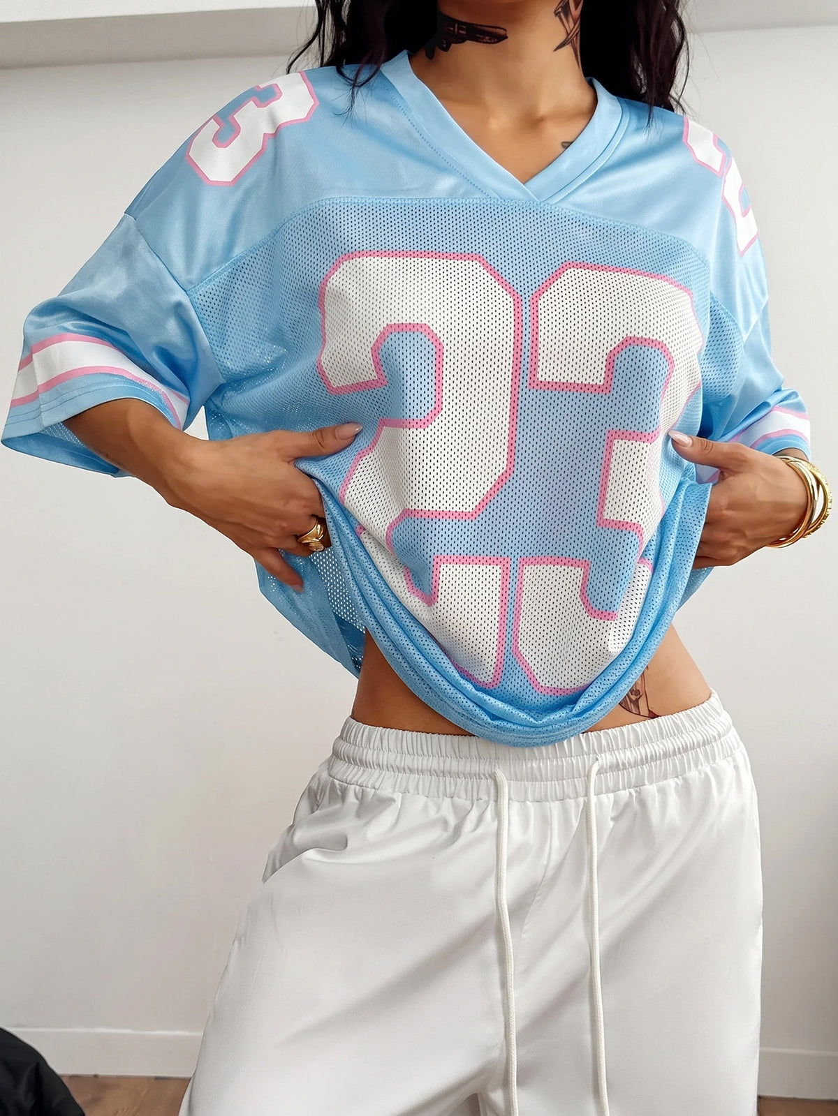 Oversized short-sleeve football jersey top featuring a V-neckline, contrast binding, and graphic number print.
