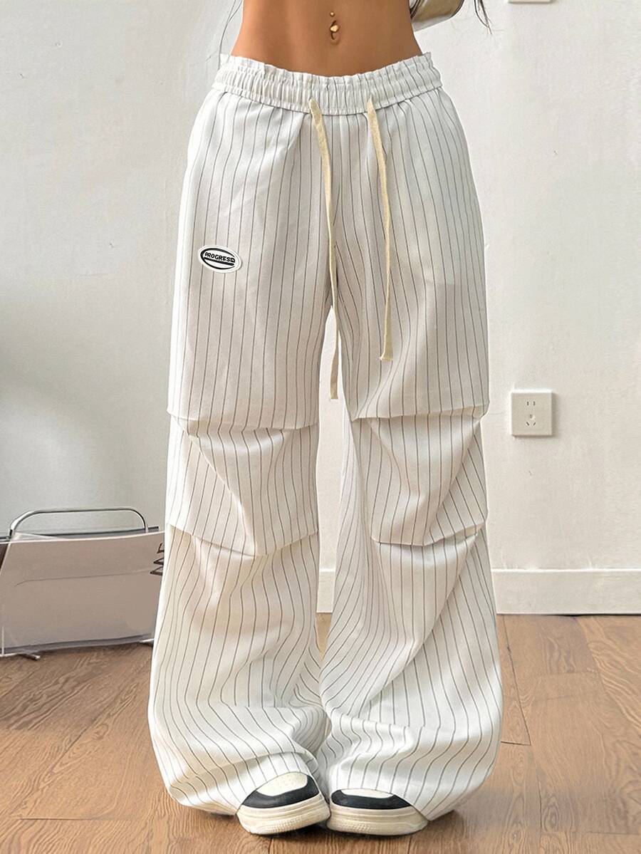 Women's black and white striped wide leg pants featuring an elastic drawstring waistband, side pockets, and a loose straight leg fit.