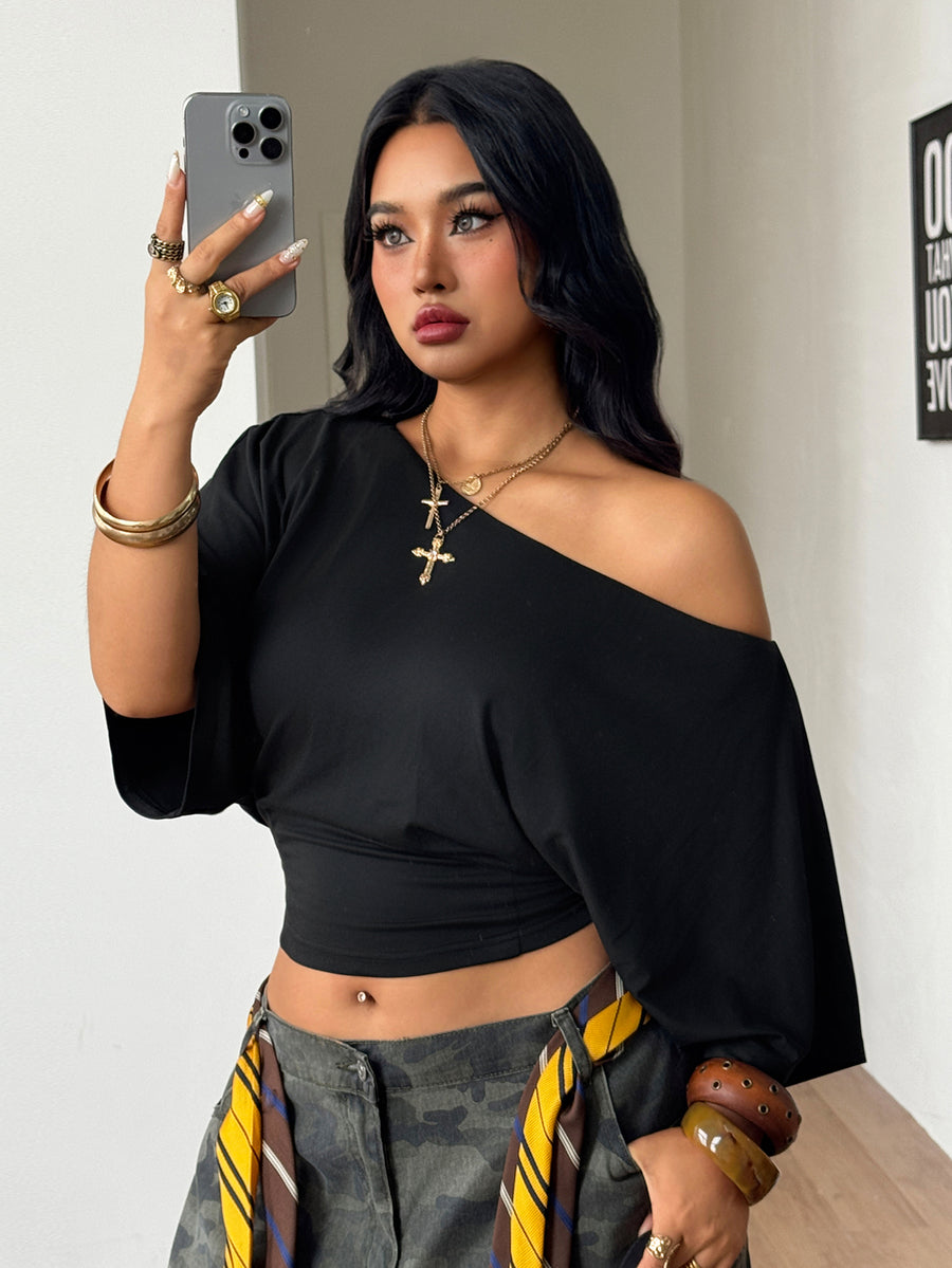 Black plus size cropped knit t-shirt featuring an asymmetrical scoop neckline, three-quarter batwing sleeves, and a loose casual fit.