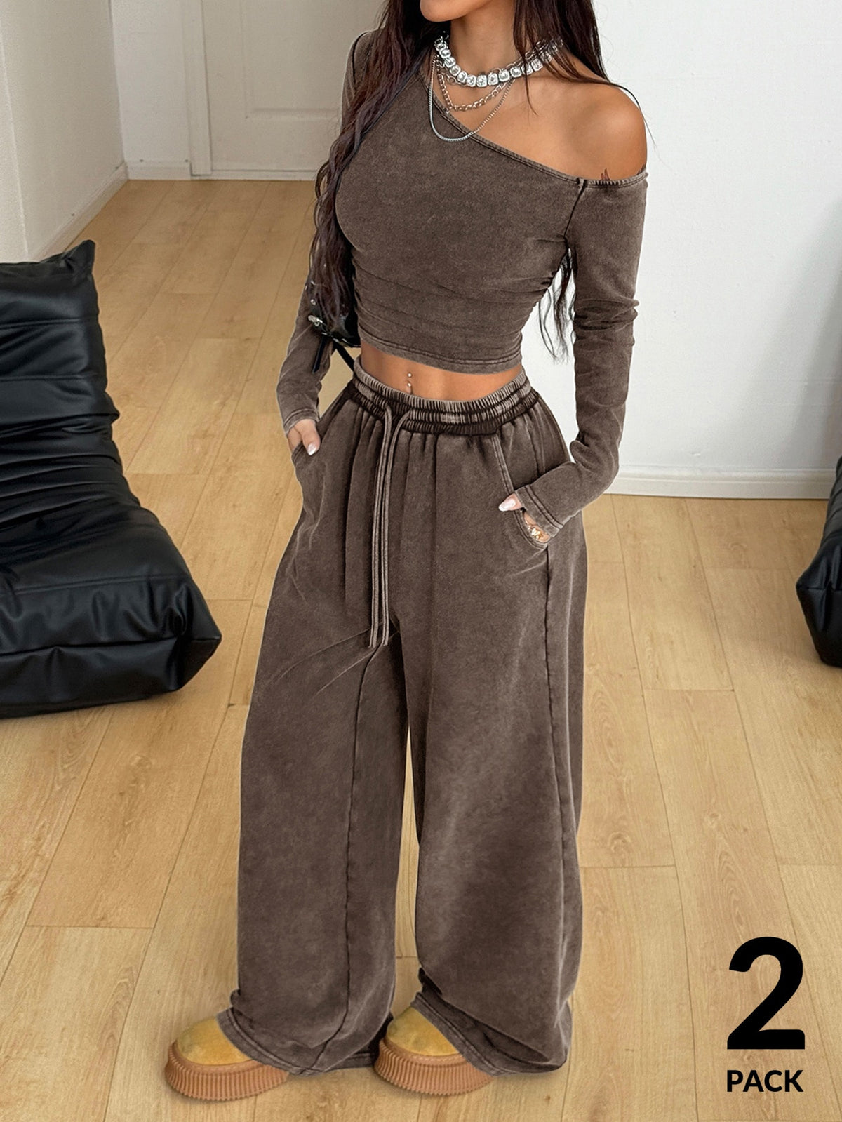 Women's two-piece knit lounge set featuring a black long sleeve asymmetrical crop top and matching high-waisted wide leg sweatpants.