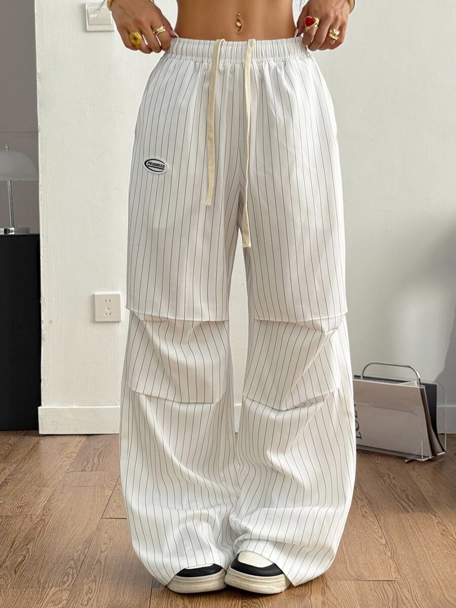 Women's black and white striped wide leg pants featuring an elastic drawstring waistband, side pockets, and a loose straight leg fit.
