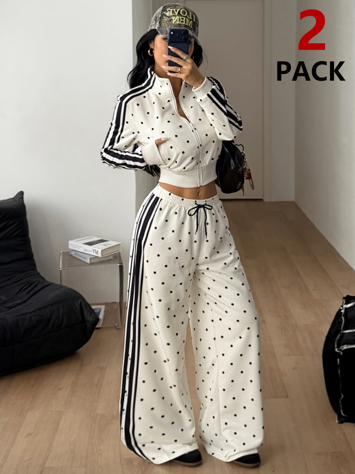 Women's two-piece black and white polka dot set featuring a short zip-up mock neck sweatshirt and matching wide-leg sweatpants.