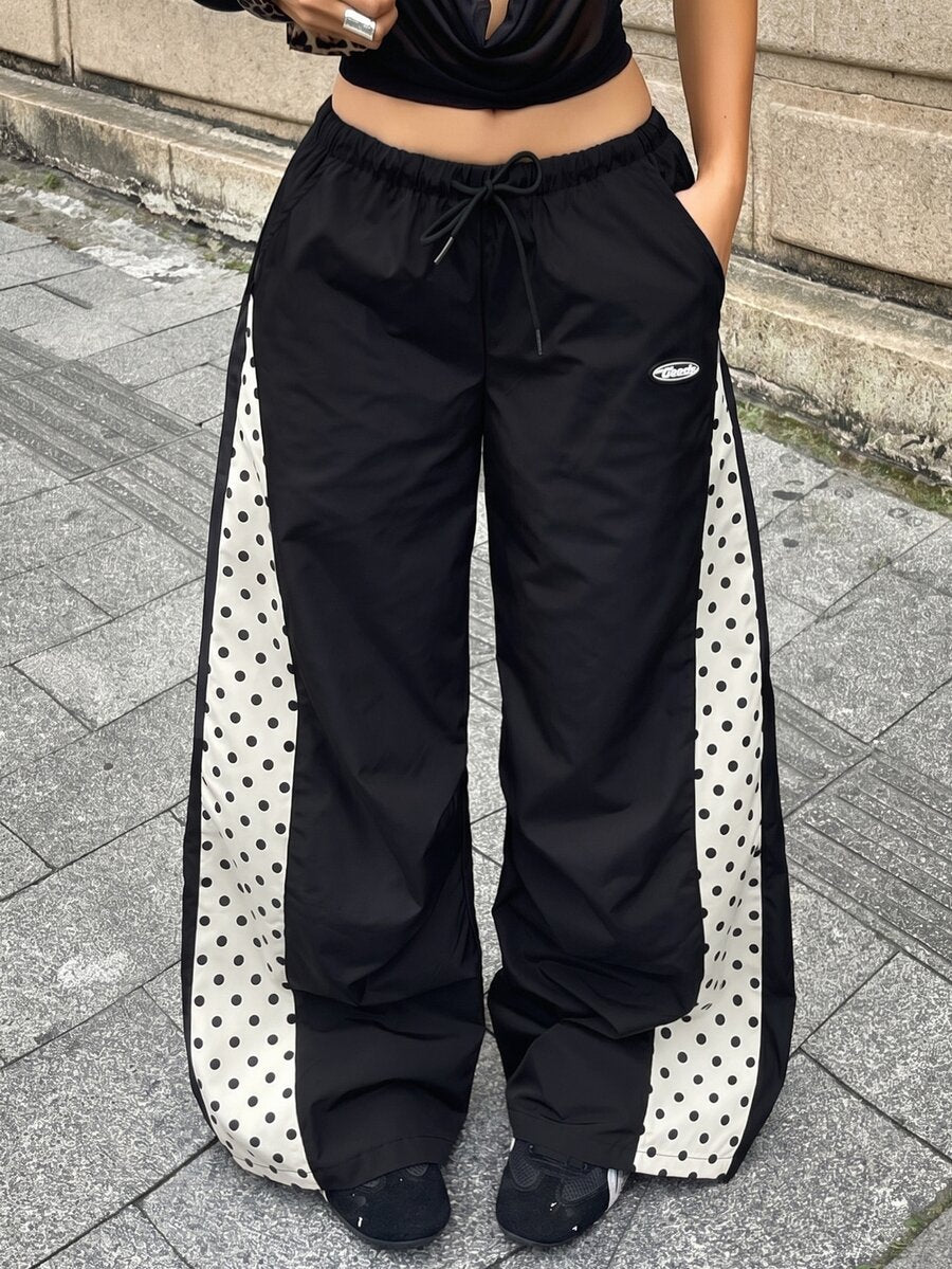 Women's black baggy jogger pants with an adjustable drawstring waist and colorblock polka dot geometric pattern.