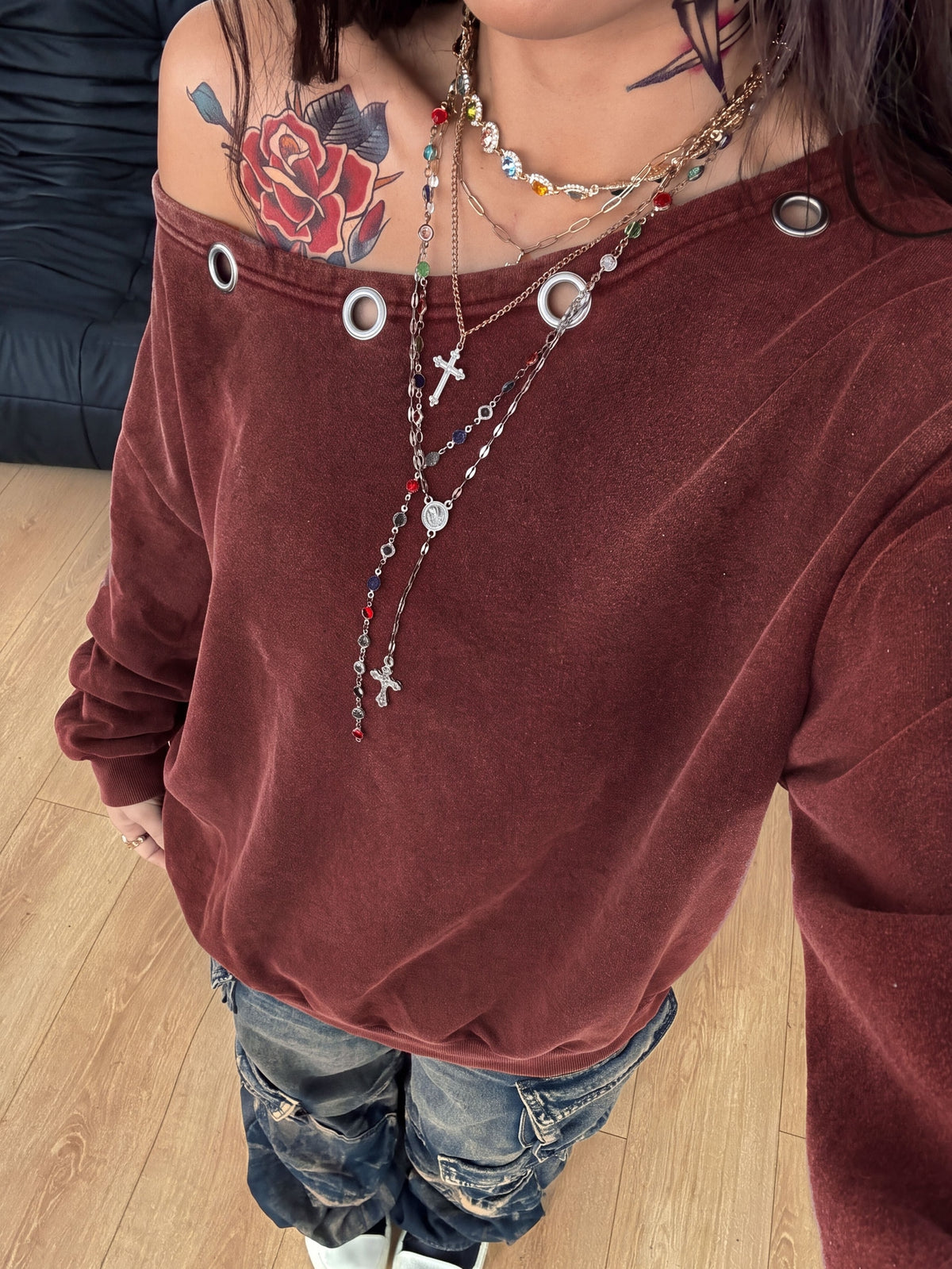 Women's oversized dark grey long sleeve sweatshirt featuring an asymmetrical boat neckline with grommet eyelet details and drop shoulders.