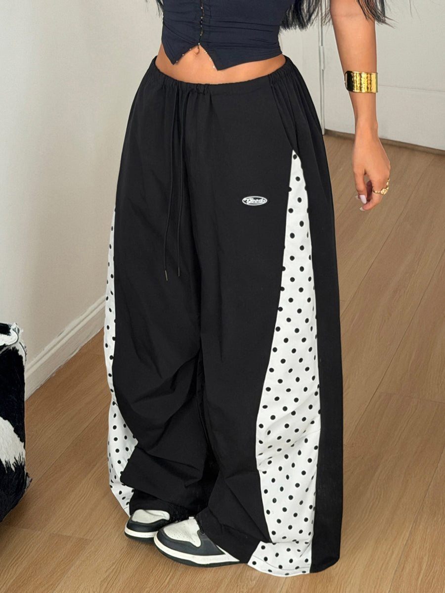 Women's black baggy jogger pants with an adjustable drawstring waist and colorblock polka dot geometric pattern.