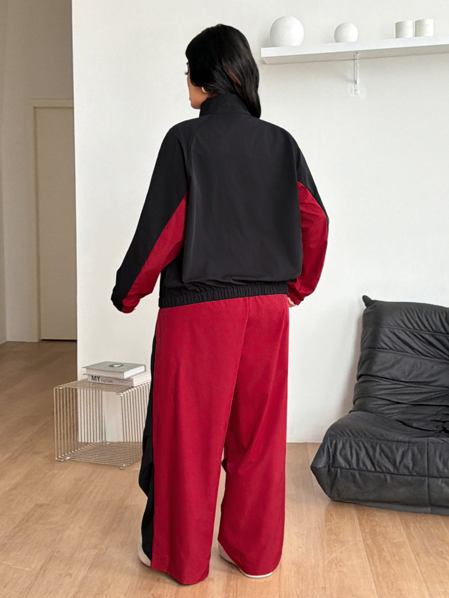 Women's plus size two-piece casual tracksuit set in black, featuring a loose-fit zip-up jacket with stand collar and matching cropped parachute pants.